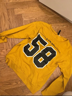 Gul långärmad topp med tryck - Cool gul långärmad topp med stort svart och vitt tryck av siffran 58 på ryggen och texten 'Game On' ovanför. Tillverkad i mjuk bomull, perfekt för en avslappnad och sportig stil.