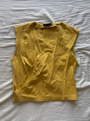 Gul omlottopp från mango - Snygg gul ärmlös omlottopp från mango med djup V-ringning. 