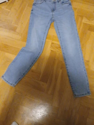 Ljusblå raka jeans i klassisk modell - Ljusblå jeans med rak passform och hög midja. Klassisk femficksdesign och dragkedja med knapp. Perfekta till vardagslooken och lätta att matcha med olika stilar. Tillverkade i denim för en tidlös känsla.