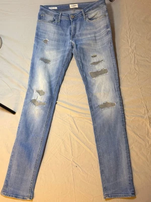 Jack & Jones blå jeans – Slim fit – 31/34 – Slitningar – Mycket bra skick - Jack & Jones blå jeans – Slim fit – 31/34 – Slitningar – Mycket bra skick  Snygga blå Jack & Jones slim jeans, storlek 31/34, i mycket bra skick. Har stilrena slitningar som ger en levande och trendig denimlook.  Slim fit som sitter snyggt längs benen och funkar perfekt till sneakers, hoodie eller mer clean outfits.  Mått: Midja: 39 cm Längd: 107 cm  • Märke: Jack & Jones • Passform: Slim • Färg: Blå med slitningar • Skick: Mycket bra  Jack & Jones 5  Hashtags: #jackandjones #slimjeans #bluejean