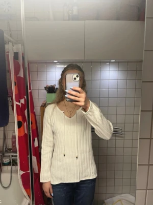 Vit stickad tröja med v-ringning - Jag säljer denna vita stickade tröja med v-ringning och pärlor.  Tröjan är i fint skick förutom de mörkare pärlorna som har tappat lite färg.  Skriv om du har några frågor eller vill ha fler bilder💕