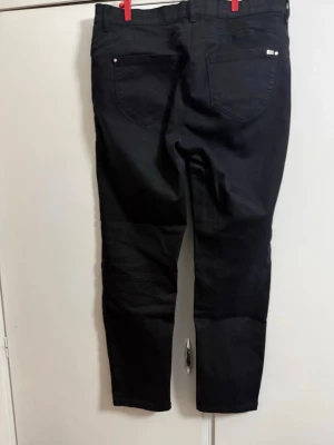 Svarta raka jeans med hög midja från Breal - Säljer ett par svarta jeans med rak passform och hög midja. Klassisk femficksmodell med bälteshällor och knappgylf. Jeansen har en stilren look och passar perfekt till en trendig vardagsoutfit.