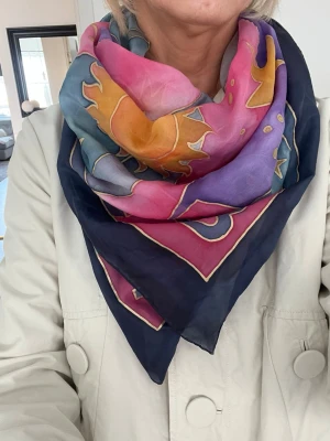 Färgglad mönstrad sidenscarf - Säljer en snygg fyrkantig scarf i siden med färgstarkt mönster i blått, rosa, lila, orange och gult. Scarfen har en lyxig känsla och är perfekt att knyta runt halsen för en cool och personlig stil.