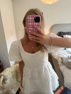 Vit kort klänning med spets - Intressekoll!!Söt vit kortklänning med broderade blommönster och volangkant. Klänningen har korta ärmar, v-ringad hals och fina spetsdetaljer. Slutsåld ifrån meet me there. Aldrig använd endast testad en gång, med prislapp kvar. 🥰