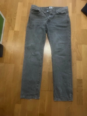Grå raka jeans  - Ett par grå jeans med rak passform och klassisk femficksdesign. Jeansen har råa kanter vid bensluten för en avslappnad look. Perfekta för dig som gillar vintage vibe och enkel stil. Materialet är denim i bomull.
