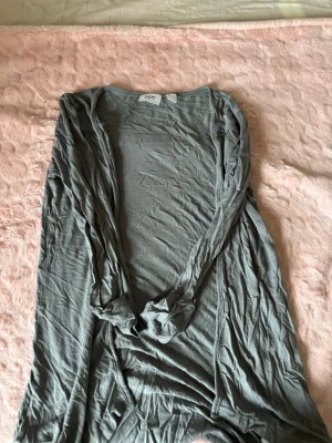 Ljusgrå tunn kofta från Esprit - Tunn och lätt ljusgrå kofta från Esprit med öppen front och långa ärmar. Perfekt att slänga över en t-shirt eller linne för en avslappnad look. Materialet känns mjukt och följsamt.