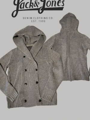 Grå stickad hoodie från Jack & Jones - Snygg grå stickad cardigan från Jack & Jones Originals med dubbelknäppning framtill och breda ribbade muddar. Tröjan har en stor huva och är tillverkad i ett grovstickat material som ger en avslappnad look.