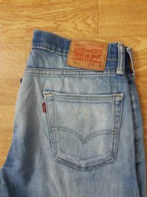 Levi's 513 ljusblå jeans  - Säljer ett par klassiska Levi's 513 jeans i ljusblå tvätt. Jeansen har rak passform, fem fickor och den ikoniska läderlappen bak i midjan. Tillverkade i slitstark denim med snyggt sliten look och röda Levi's-taggen på bakfickan.