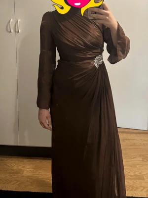 Brun långklänning hel ny oanvind s/m - Beställde denna klänning utomlands och den passade inte mig. Vill sälja den nu för billigt pris. Den är heltny och oanvänd.
