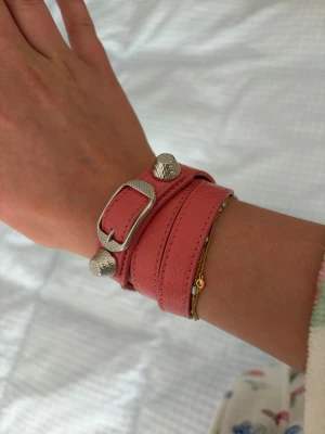 Rosa Balenciaga läderarmband - Snyggt rosa armband från Balenciaga i äkta läder. Armbandet har en cool dubbelwrap-design med silverfärgade nitar och spänne som detaljer. Äktahetsbevis tillkommer💖💖