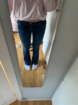 Mörkblå bootcut jeans - Snygga mörkblå bootcut jeans med klassiska fickor och kontrastsömmar. Jeansen har en låg midja och är tillverkade i ett stretchigt denimtyg som sitter skönt. Perfekta för en avslappnad och trendig look.    Storlek: 26/34