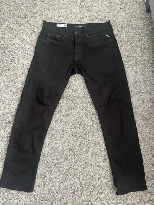 Svarta Replay  jeans   - Snygga svarta jeans från Replay, modell Grover. Helt nya utan prislapp. Klassisk femficksdesign med smal passform och svarta sömmar. Jeansen har Replay-logga på myntfickan och är tillverkade i stretchigt material för extra komfort.