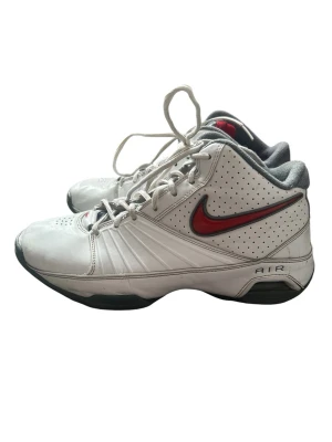 Nike Air Jordan skor - Nike Air sneakers i vitt med röd swoosh på sidan och grå detaljer. Modellen har perforerade partier för ventilation, klassisk snörning och vadderad krage. Snygg sportig look med AIR-dämpning i sulan för extra komfort.