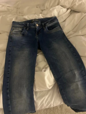 Ltb jeans - Säljer ett par blå bootcut jeans från ltb med klassisk femficksmodell och snygga slitningar på låren. Jeansen har normal midja och är tillverkade i denim med lite stretch för skön passform. Perfekta till vardagslooken!