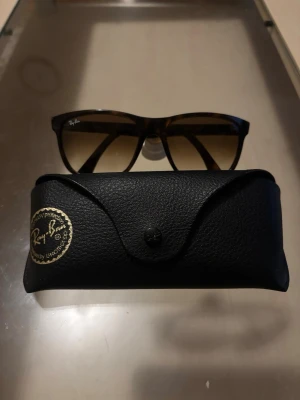 Ray-Ban boyfriend solglasögon - Snygga solglasögon från Ray-Ban med brunmelerad båge och fyrkantiga glas. Kommer med original svart fodral i skinnimitation. Perfekta för att lyfta din stil under soliga dagar. Prisförslag är jag öppen för, men håll det solklart 😎
