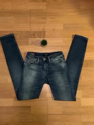 Blå skinny jeans från Replay - Snygga blå skinny jeans från Replay med klassisk femficksdesign och diskreta slitningar framtill. Jeansen har en smal passform och är tillverkade i stretchigt denim för en bekväm känsla. Perfekta för dig som gillar en modern och stilren look.