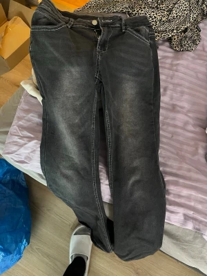 Svarta bootcut jeans med slitningar - Snygga svarta bootcut jeans med lätt slitna detaljer och klassiska fem fickor. Jeansen har en något utsvängd passform nertill och kontrastsömmar. Perfekta för en avslappnad och trendig look.