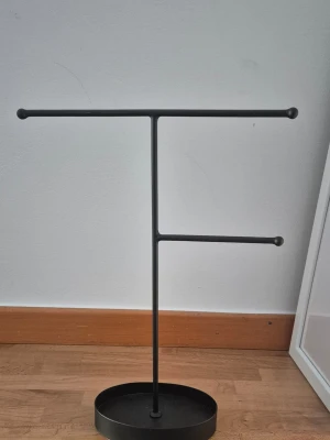 Svart smyckesställ i metall - Svart smyckesställ i metall med två armar i olika höjd för att hänga halsband, armband eller örhängen. Oval bas för stabilitet och minimalistisk design som passar perfekt på sminkbordet eller byrån. Höjd ca 29 cm. Skriv om du har frågor 🌸 