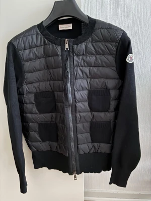 Moncler cardigan jacka - Nyskick moncler jacka/cardigan, jacka till dam. I storlek 3, passar dig som har S/M då den är i väldigt liten i storleken. QR kod och NFC Scan funkar som den ska. Skickar med dust bag som jackan kan förvaras i. Kvitto finns även. 