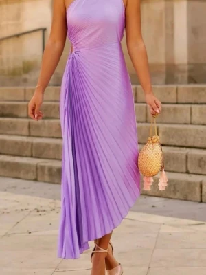Lila plisserad oneshoulderklänning - Snygg lila långklänning med plisserad kjol och oneshoulder-design. Klänningen har en elegant asymmetrisk axel och är tillverkad i ett glansigt material som ger en lyxig känsla. Perfekt för dig som vill sticka ut med stilren och modern look.