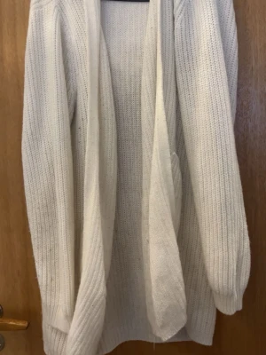 Vit stickad öppen kofta - Mysig vit stickad kofta med öppen front och långa ärmar. Koftan är nopprig som syns på bilder så pris går att sänka