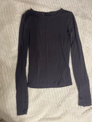 Tight topp  - En enkel och stilren mörkblå långärmad topp med rund halsringning. Perfekt att matcha med jeans eller kjol för en clean look. Tillverkad i mjukt material som känns skönt mot huden.