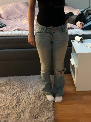 Ljusblå bootcut jeans med slitning - Säljer ett par ljusblå bootcut jeans. Från bershka, finns ett hål på ena benet nere vid foten men inget stort som kan bli mycket värre!☺️