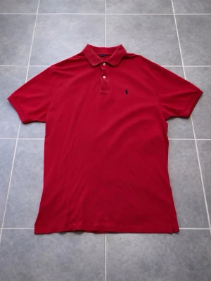 Ralph Lauren pikétröja  - Klassisk röd pikétröja från Ralph Lauren med broderad marinblå logga på bröstet. Tröjan är i nyskick och har knappt använts. Hör av dig vid intresse / frågor. PRIS KAN DISKUTERAS. 