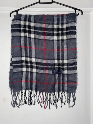 Grå Halsduk från Burberry - Grå halsduk från Burberry i 100% merinoull. Väldigt fint skick till ett bra pris. Mitt pris: 399kr