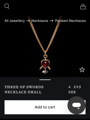 Three of Swords halsband guld - Unikt halsband med guldfärgad kedja och ett hänge format som ett hjärta med tre svärd. Hänget har en röd, glansig sten i mitten som ger en cool kontrast mot guldet. 