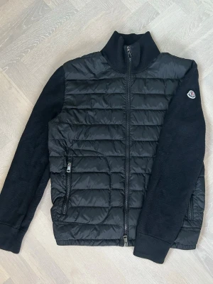 Moncler Cardigan - Svart Moncler Tricot Down Cardigan | Nypris: 10 000kr | Size: L | Skick: 8/10 | Äktenhetsbevis från GarmsMarket (se bild) | Hör av dig vid minsta fråga eller fundering//                                                     Den är tvättad hårt, observera att den är liten i storleken!