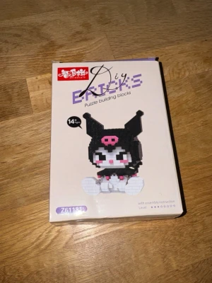 DIY byggsats Kuromi byggklossar - Säljer en DIY byggsats med små byggklossar som föreställer Kuromi från Sanrio. Setet är svart, vitt och rosa och kommer i originalförpackning med instruktioner. Perfekt för dig som gillar pyssel och samlarfigurer. Mått ihopbyggd: 9.8x7.8x7.8cm
