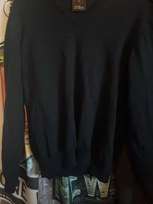 Mörkblå stickad tröja Oscar Jacobson - Snygg mörkblå stickad tröja från Oscar Jacobson med klassisk V-ringning och långa. Använd men i mycket bra skick