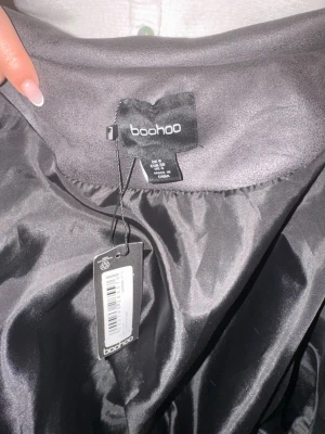 Grå bomberjacka från Boohoo - Snygg grå bomberjacka från Boohoo med två stora bröstfickor och dragkedja framtill. Jackan har ribbade muddar vid ärmslut och midja samt en klassisk krage. Materialet är syntet och jackan har en croppad passform.