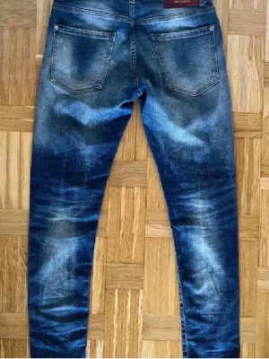 Dsquared Jeans - Säljer ett par snygga blå skinny jeans med slitningar och lätt tvättad look. Jeansen är från Dsquared med ett klassisk femficksdesign och smal passform. Perfekta för en avslappnad och trendig stil.