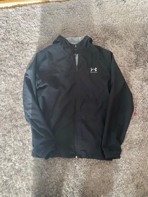 Under Armour Vindjacka - Knappast använd vindjacka som jag säljer då den blivit för liten för mig. Inga defekter alls och är som ny!