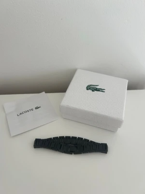 Svart klockarmband från Lacoste - Snyggt svart klockarmband från Lacoste i klassisk länkdesign. 20 cm är armbandet men går att justera med ett länkverktyg. 