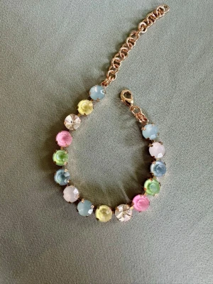 Färgglatt armband - Snyggt armband i pastellfärger som rosa, blått, gult, grönt och vitt. Armbandet har guldfärgad kedja och justerbart spänne. Perfekt för dig som gillar färg och vill sticka ut lite extra. Storlek 17-22 cm.