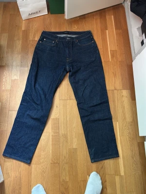 Mörkblå raka jeans från Abercrombie & fitch - Säljer ett par mörkblå jeans från Abercrombie & fitch med rak passform och klassisk femficksdesign. Jeansen är tillverkade i kraftig denim och har en enkel, stilren look utan slitningar eller tvättade detaljer. Perfekta för en clean och tidlös stil.