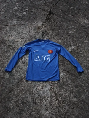Manchester United 07/08 - Cristiano Ronaldo - Snygg blå långärmad Manchester United tröja från Nike med klubbmärke på bröstet och AIG som sponsortryck. Liten tråd från Nike loggan har lossnat men bortsett från det väldigt fin.
