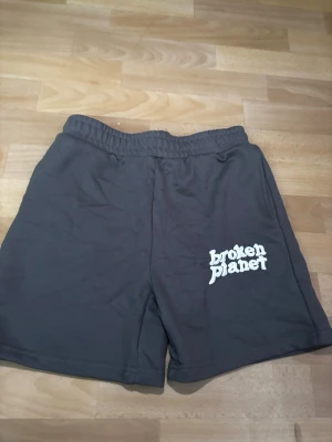 Shorts Broken Planet Logo 🪐 - Stylish Broken Planet sweatshorts in black, featuring an elastic waistband for comfort and a distinctive white "broken planet" logo print on the left leg. These shorts include a practical back pocket and are crafted from a soft cotton blend, perfect for casual wear.  ⭐️ Condition : 9/10 🎲 Size : MEDIUM 🎨 Color : Black 📦 Fast and careful shipping