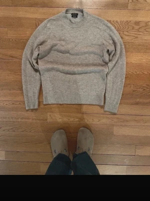 Grå stickad tröja Massimo Dutti - OBS färgen har tappats lite så den ser lite beige ut. Säljer en stilren grå stickad tröja från Massimo Dutti. Tröjan har rund halsringning och ribbade muddar vid ärmslut och nederkant. Tillverkad i mjukt material som känns lyxigt och passar perfekt till lager på lager. För