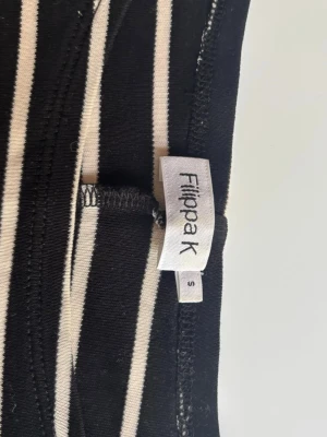 Randig långärmad topp från Filippa K - Snygg långärmad topp från Filippa K i svart och vitt med horisontella ränder. Toppen har en rak passform och är tillverkad i mjukt material som känns skönt mot huden. Perfekt att styla med jeans eller kjol för en enkel men trendig look.