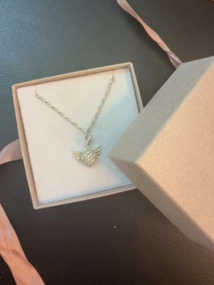 Silverarmband i 925s  från Thomas Sabo - Säljer ett silverfärgat armband med en kedja och ett hängsmycke i form av en ängel i 925s. Ängeln är dekorerad med små glittrande stenar som ger ett lyxigt intryck. Levereras i en elegant ask med rosa band. Perfekt som present! Helt nytt skick.    
