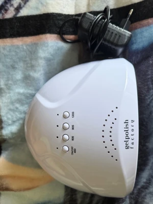 UV LED lampa från Gelpolish Factory - UV LED lampa för naglar från Gelpolish Factory. Vit, kupolformad design med flera timerinställningar (60s, 90s, 120s) och många LED-lampor för jämn härdning av gelélack. Perfekt för både manikyr och pedikyr hemma.
