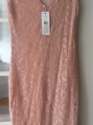 Rosa spetsklänning från Bubbleroom - Söt rosa spetsklänning från Saint Tropez med v-ringning och figurnära passform. Klänningen är kort och har ett vackert spetsmönster över hela plagget. Perfekt för sommarens alla tillfällen!