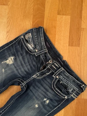 Mörkblå slitna Vigoss jeans - jättefina lågmidjade mörkblåa jeans från vigoss med slitningar och vita sömmar. de passar mig som är 167 lång jättebra. jag brukar ha 34/36 i andra jeans för referens💓