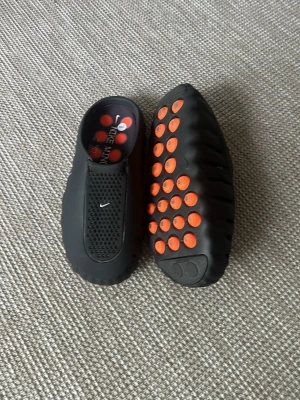 Nike Mind svart-orange tofflor - Säljer de svarta Nike mind 001. Som ni kan se på sulan är de SMÅTT använda. Tofflorna passar helt enkelt inte mina fötter så jag vill sälja iväg de. De är storlek 43 men passsar aningen mindre i storlek. Jag köpte de för 1800 så vill helst inte förlora för mycket på de! Va snabba med ert köp de här flyger nog av hyllan fort. Sista bilden är för storleks referens!!!