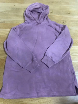 Ljuslila hoodie från 157 - Mysig ljuslila hoodie från 157 med huva och långa ärmar. Tillverkad i mjukt material med borstad insida för extra komfort. Perfekt för dig som gillar en enkel och avslappnad stil.