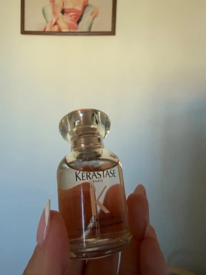 Kérastase Paris Elixir Parfum 30ml - Lyxig parfym från Kérastase Paris i en elegant rund glasflaska med genomskinligt lock. Doften har en varm, bärnstensfärgad ton och flaskan har en stilren design med tydlig K-logga. Perfekt för dig som vill ha en exklusiv och modern doft.